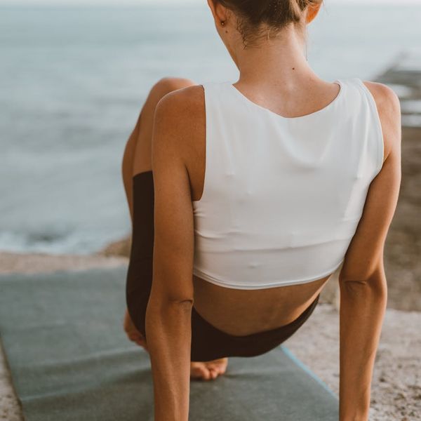 Person stretching gently outdoors during sunrise.